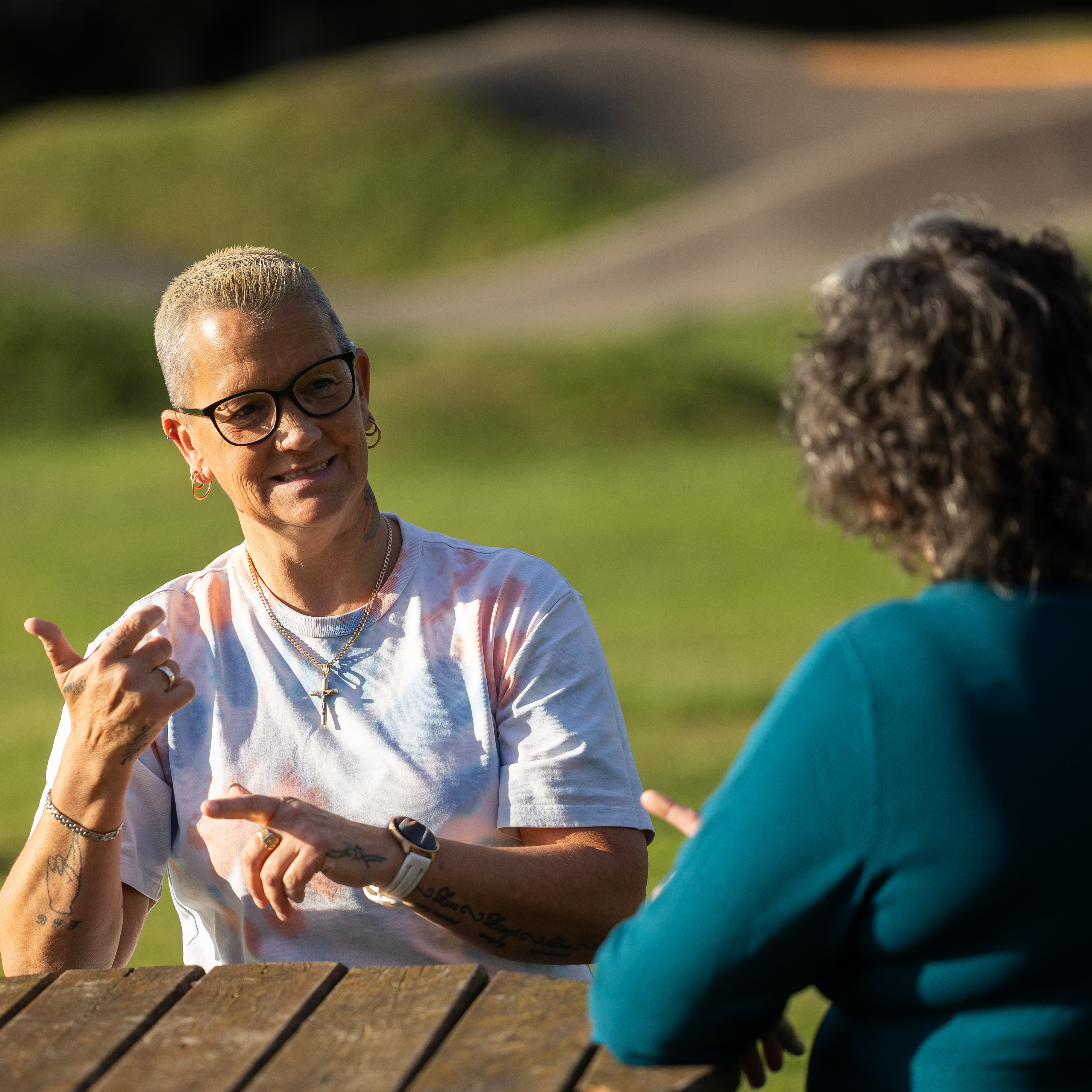 Heidi and Claire sitting at a table outside communicating with each other.