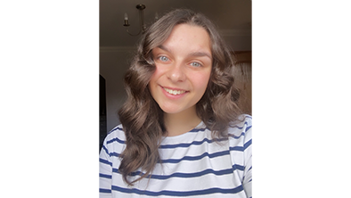 A selfie of Lee-anne. She has long brown hair and is wearing a blue and white striped top. 