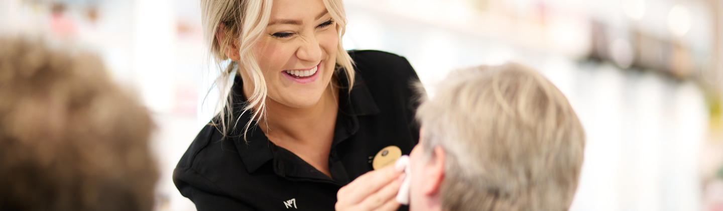 Boots No7 beauty advisor smiling and helping apply product to a customers face.