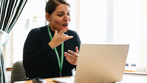 Woman sitting in front of a laptop on a video call she is using BSL.