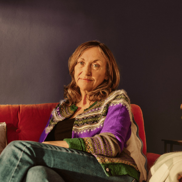 A woman is sitting on her sofa at home looking at the camera.