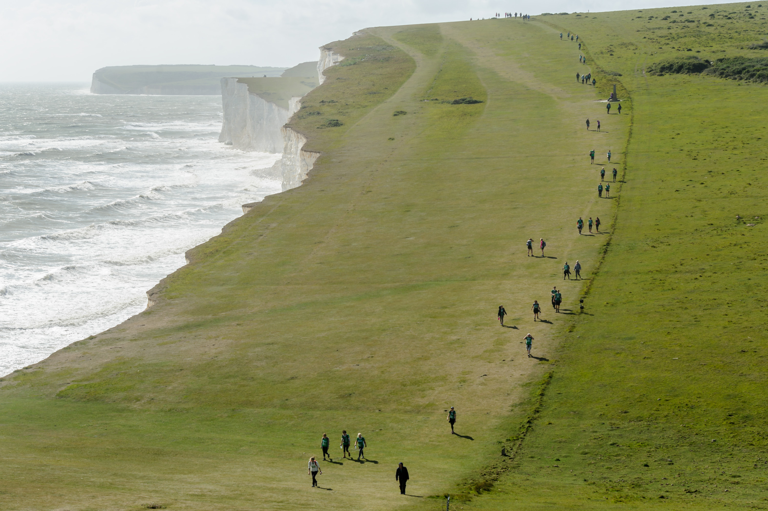 Wide angle view of South Downs Mighty Hike, with hikers walking along the cliff top