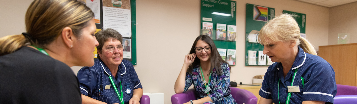 Four healthcare professionals sat around a table in discussion. One is looking through a folder of documents. 