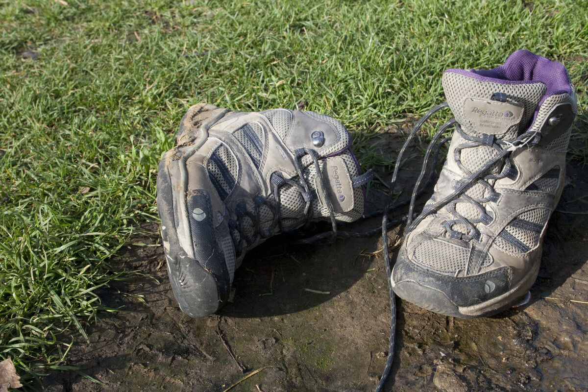 A pair of hiking boots sitting in a muddy puddle