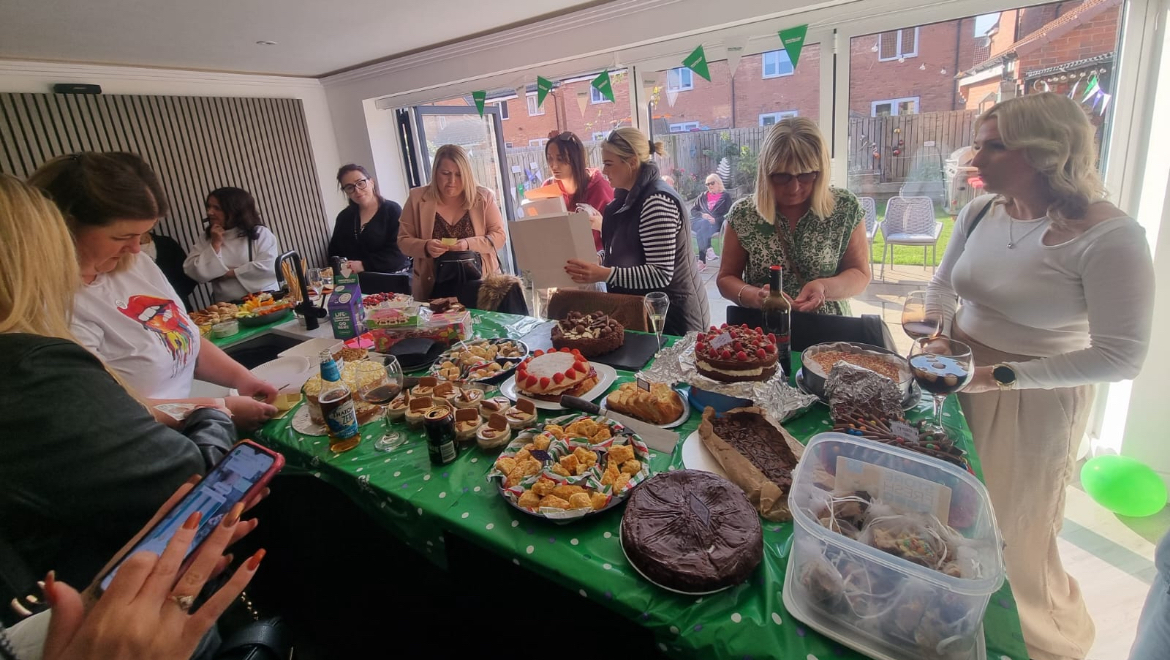 People are standing around a table decorated for a Coffee Morning.