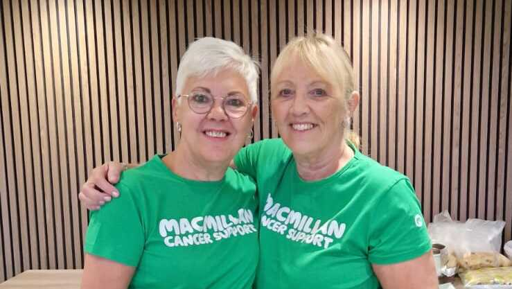 Two people are standing with an arm around each other. They are both wearing Macmillan branded t-shirts.