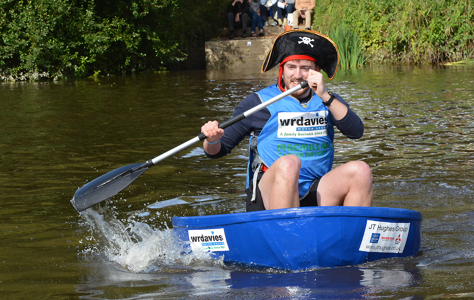 Man wearing a pirate hat paddling a coracle