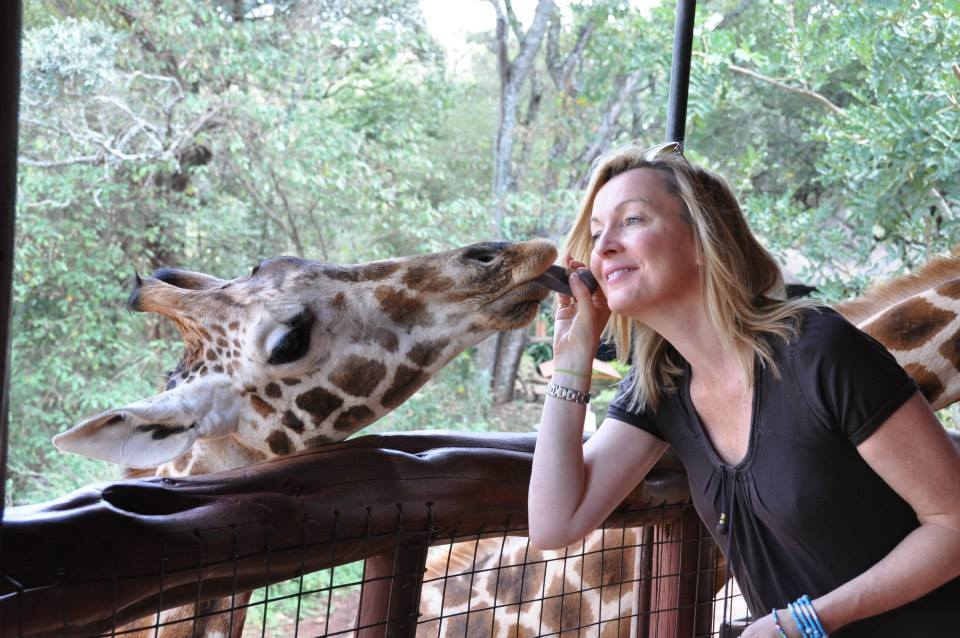 Suki next to a giraffe holding its tongue