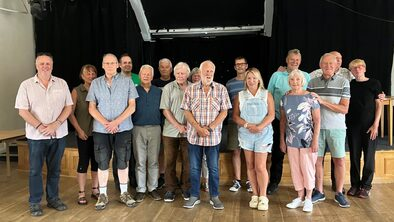 Support group members standing in front of a small stage smiling for a picture.