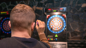 A man lining up a shot at a dart board.