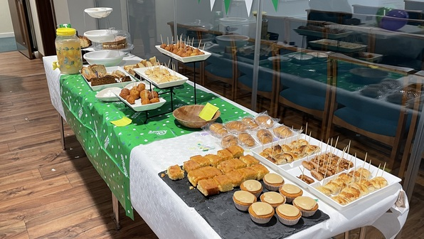 A table is decorated for a Coffee Morning at the Hackney Stoke Newington Methodist Church. It has many different dishes on it.