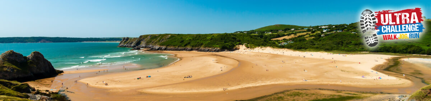 A beach at the Gower Peninsular with the Ultra Challenge logo saying Walk, Jog, Run