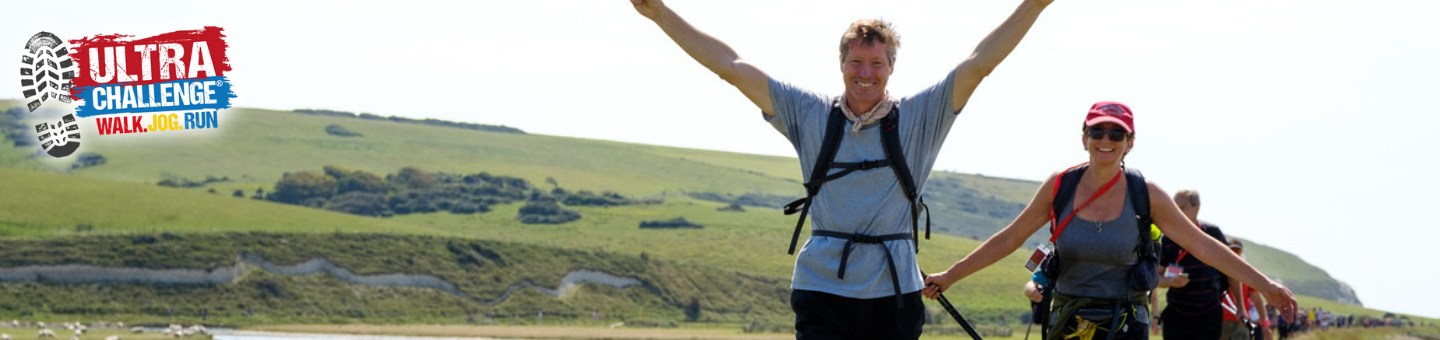 Two people walk through a grassy landscape during the Ultra Challenge event, with one raising their arms in celebration. The event logo appears in the top left corner.