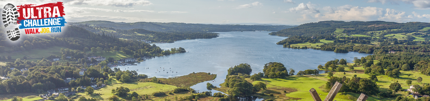 View of a lake with green hills and trees. The Ultra Challenge logo is in the top left corner