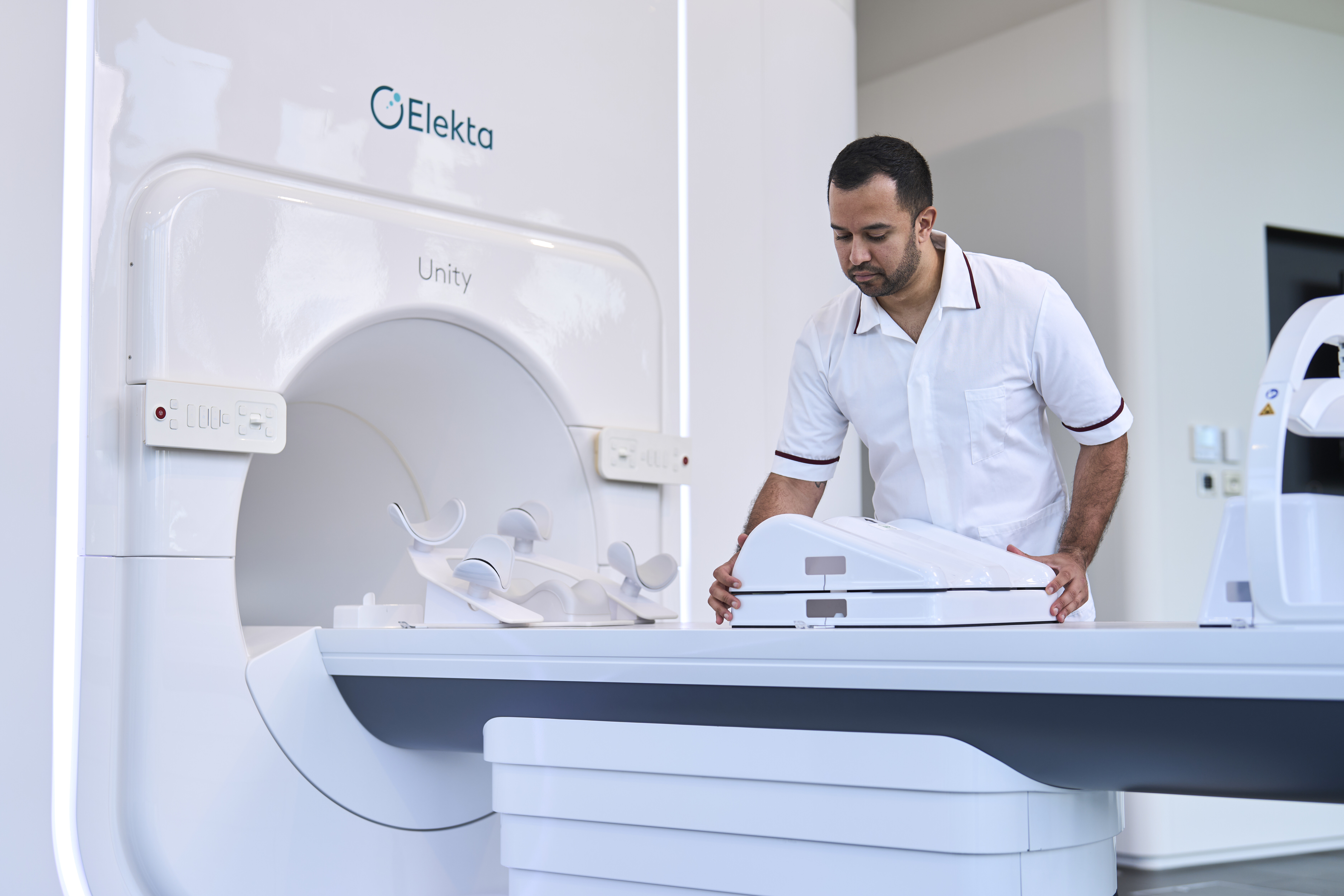 radiographer setting up a radiotherapy machine, he is wearing a white uniform.