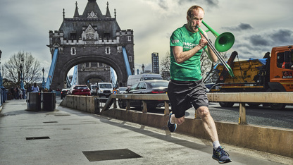 Nathaniel is captured mid leap in the air. He is playing a trombone and running across Tower Bridge. Photo by Julian Benjamin.