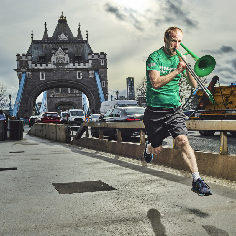 Nathaniel is captured mid leap in the air. He is playing a trombone and running across Tower Bridge. Photo by Julian Benjamin.