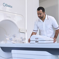 radiographer setting up a radiotherapy machine, he is wearing a white uniform.