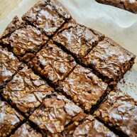 Rich and fudgy brownies are cut into square chunks and placed on white baking parchment. Photo by Michelle Tsang on Unsplash.       