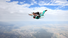 Two people strapped together in mid-air doing a tandem skydive.