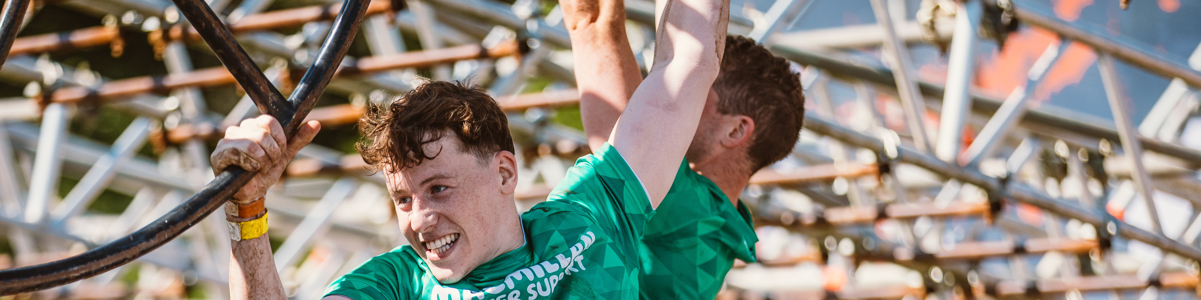 Two men wearing Macmillan t-shirts on the monkey bars