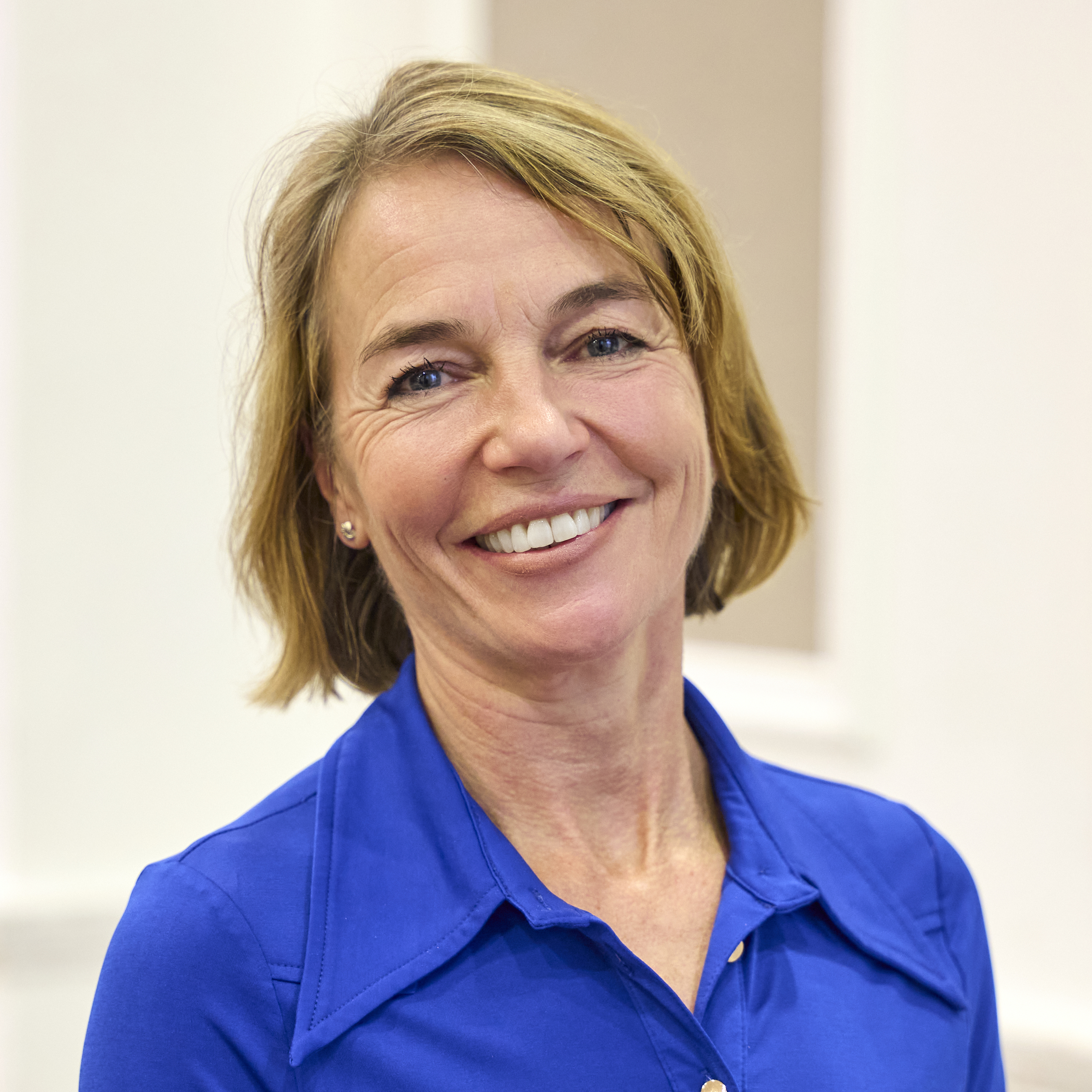 Claire is wearing a blue shirt and smiling at the camera. She has blonde hair cut into a bob.