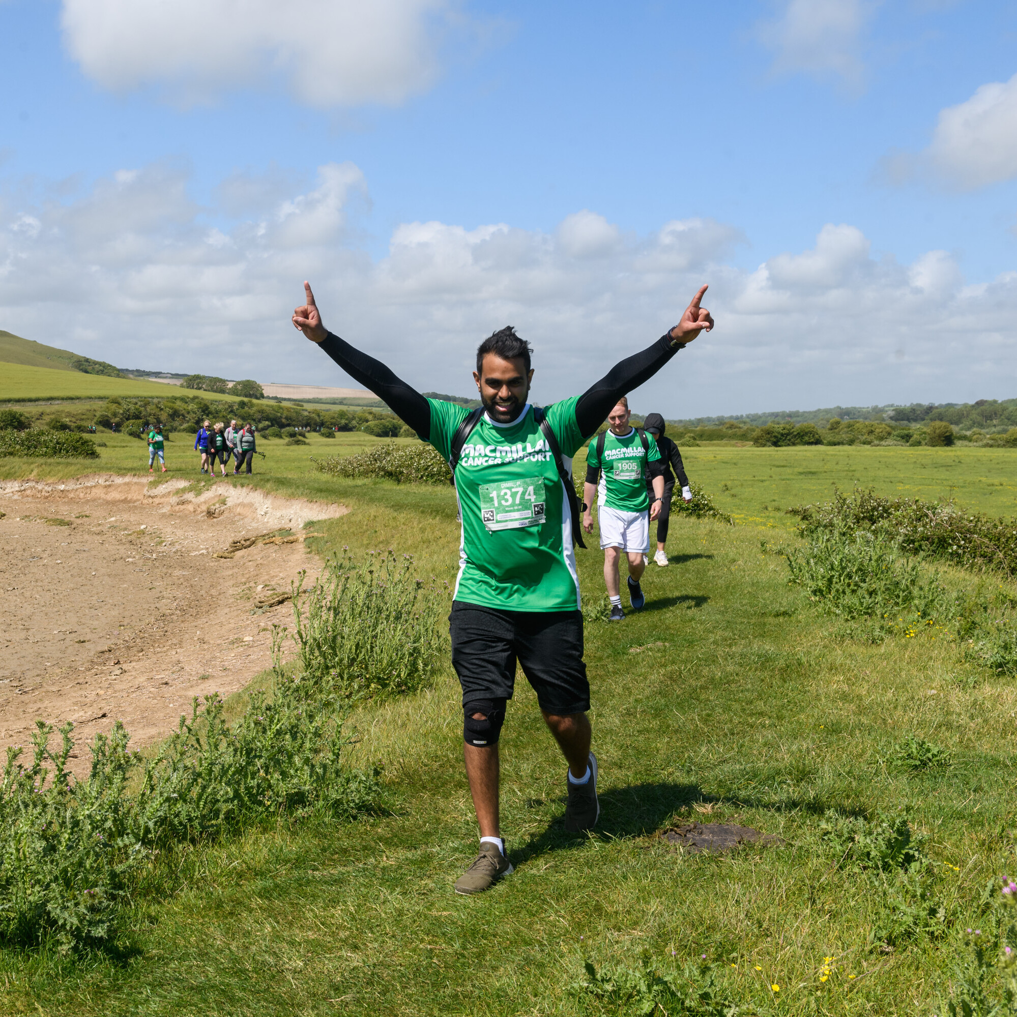 A Mighty Hikes fundraiser waves at the camera while walking along the South Downs coastline