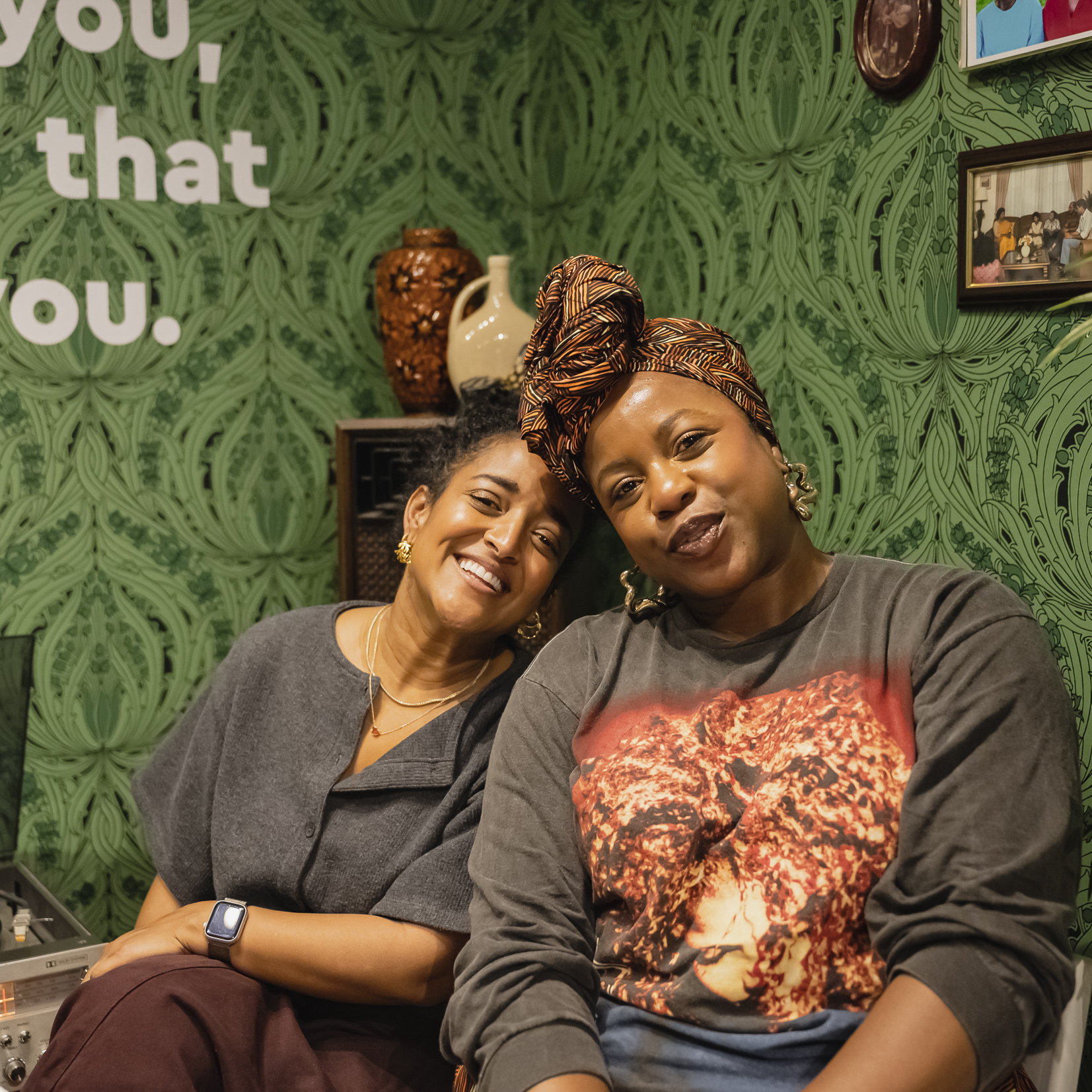 Two attendees seated closely together in a cosy corner of Macmillan Cancer Support Open House vintage living room.