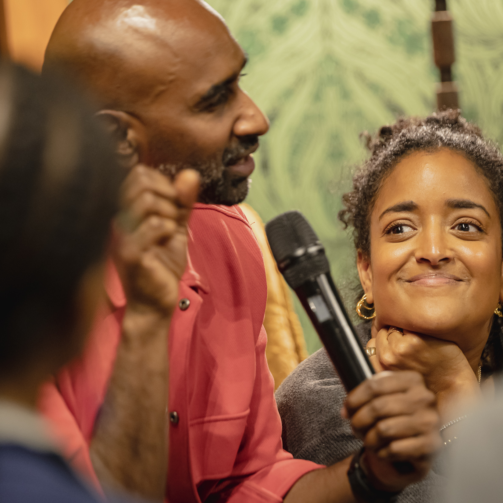 Close-up of a person speaking into a microphone during a group conversation at Macmillan Cancer Support Open House.