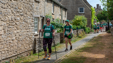 Mighty Hikers walking past stone houses