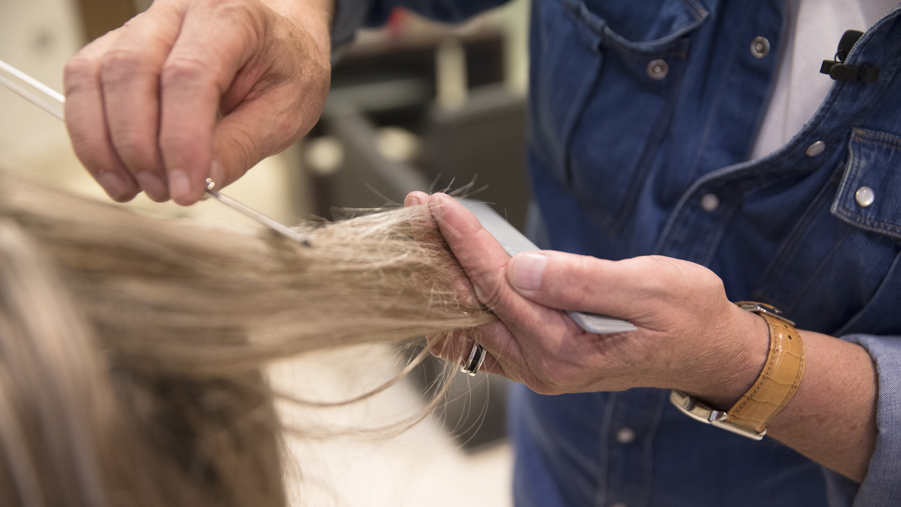 A person combs through another person's hair. The image is zoomed in on the hands.