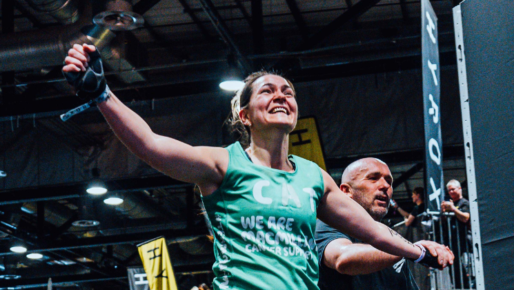 A person taking part in a HYROX. They are wearing a green Macmillan branded top. 