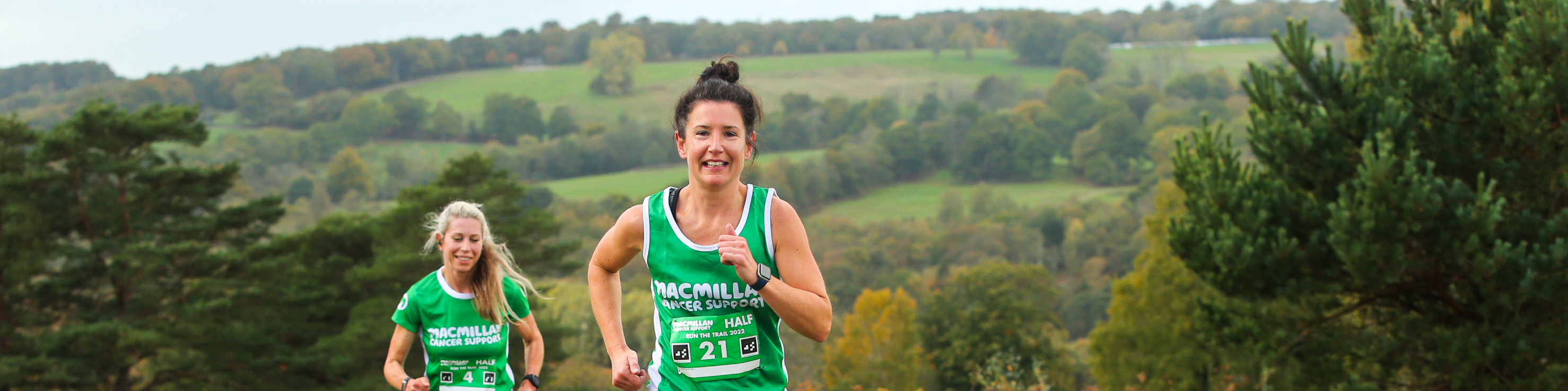 2 people running outside up a hill in Macmillan t-shirts.