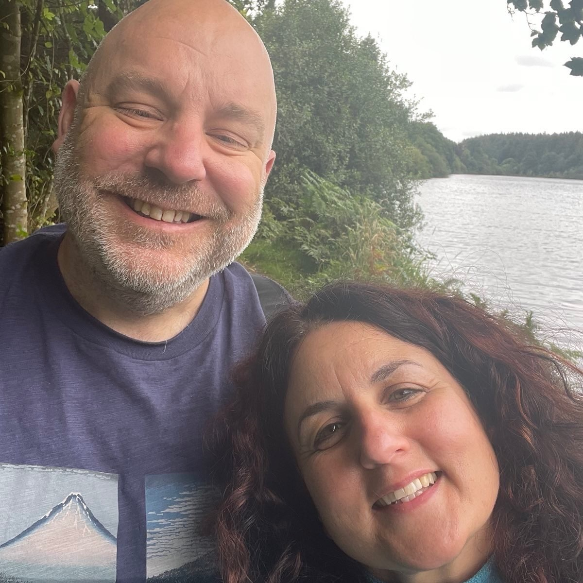 Jon is a white man with bear with his wife outside in a park.