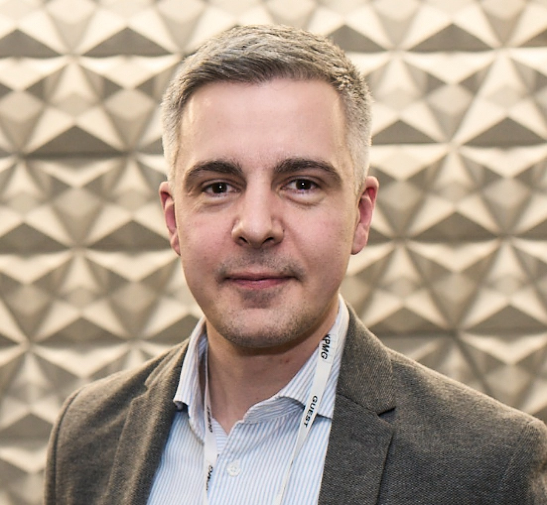 A professional photo of Michael Stickland, Head of Corporate Partnerships and Philanthropy at Macmillan. He has short hair and is wearing a pinstripe shirt and brown blazer.