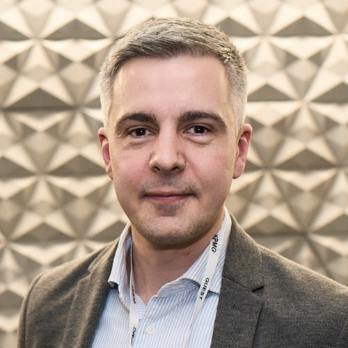 A professional photo of Michael Stickland, Head of Corporate Partnerships and Philanthropy at Macmillan. He has short hair and is wearing a pinstripe shirt and brown blazer.