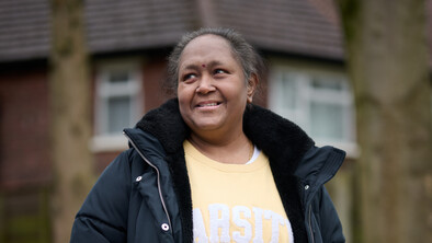 A smiling woman standing outside in a garden.