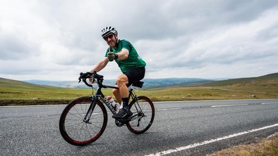 Man cycling wearing a Macmillan cycling jersey
