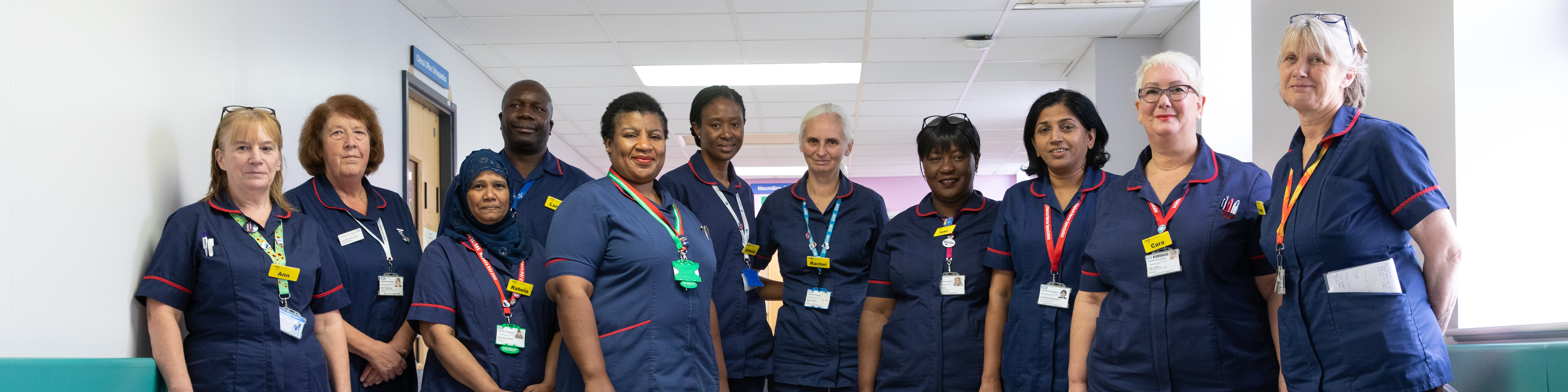 Group of nurses wearing dark blue uniforms stand in line in a hospital setting.
