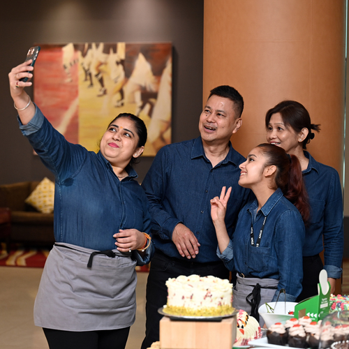 A group of employees at Aimbridge Hotel are posing for a selfie. They are celebrating at Macmillan Coffee Morning.