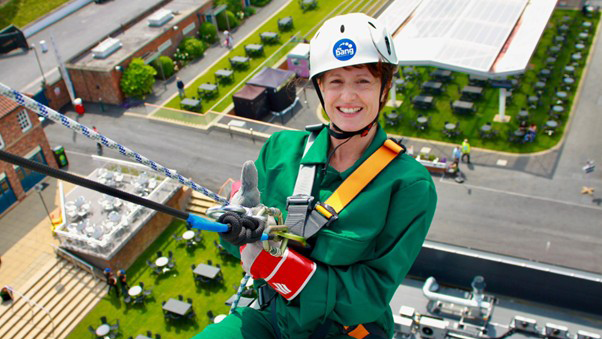 A person is abseiling in bright green attire.