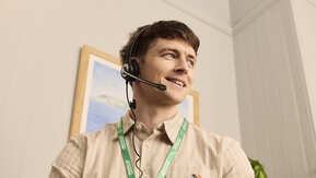 A call handler wearing a headset and lanyard in a light office environment.