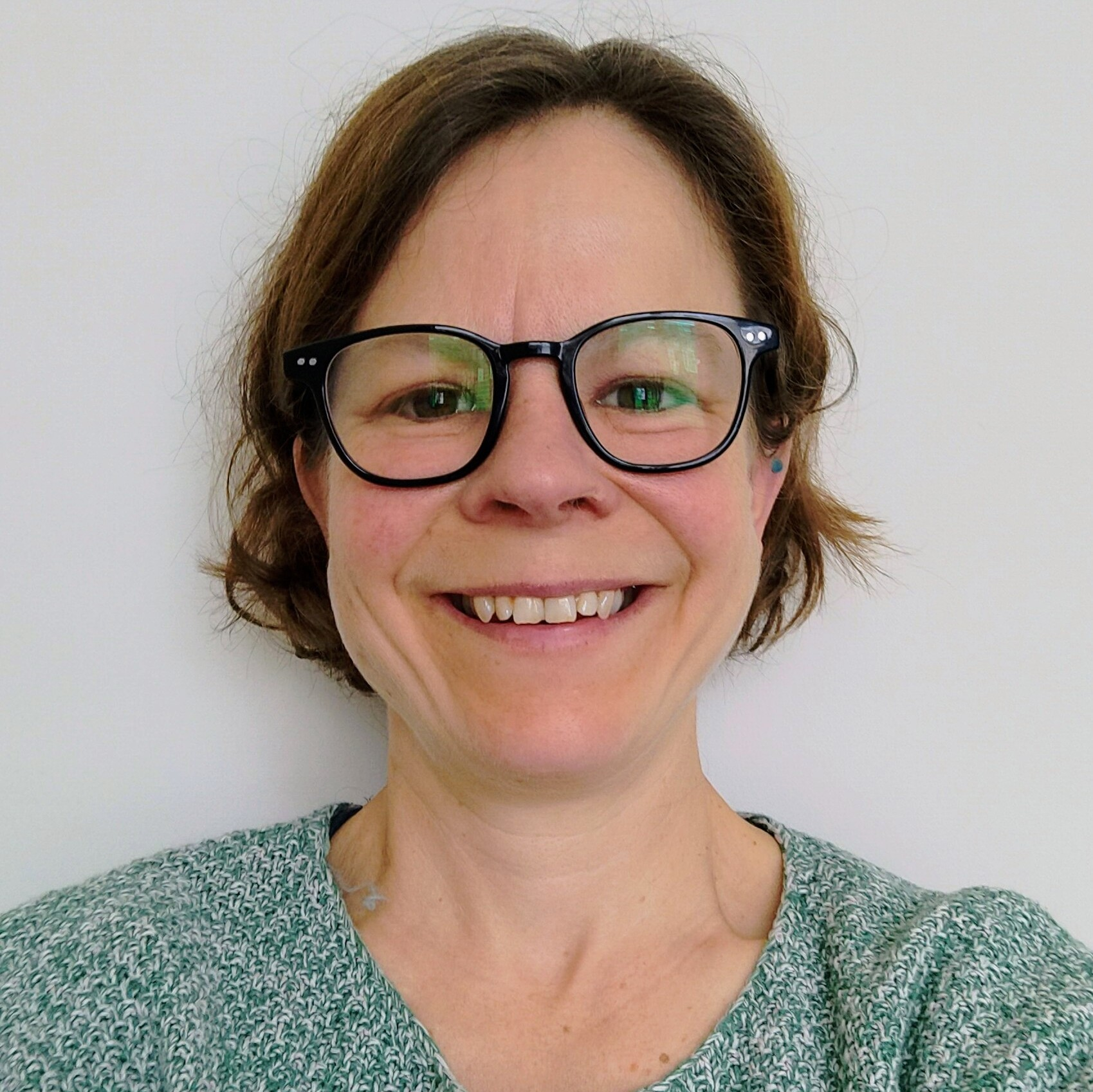 A white woman with short brown hair and glasses.