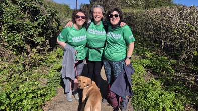 Lizzie with two other women, all wearing Macmillan t-shirts out hiking with a dog