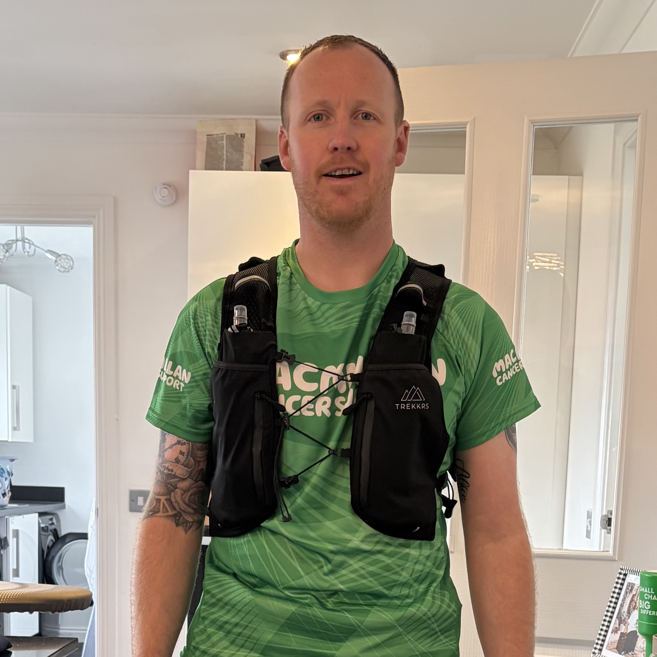 Lee in his Macmillan running vest and shorts standing in his house