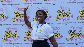 A woman in sportswear is standing in front of a banner promoting Girls Festival powered by Nike After Dark Tour