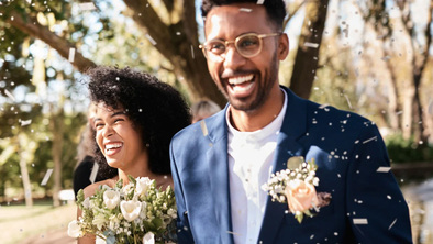 A happy couple on their wedding day with confetti in the air.