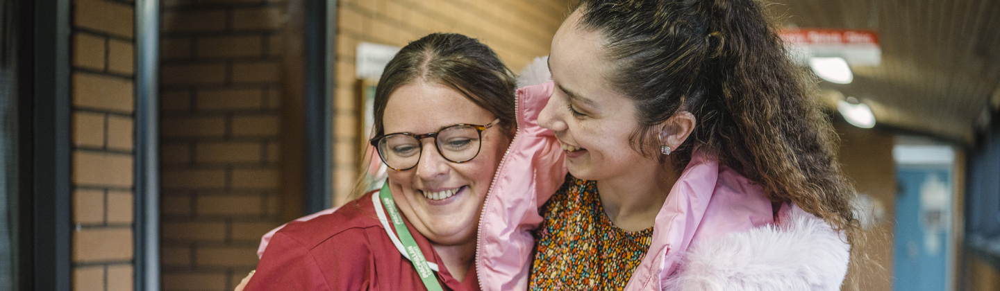 Jess and her Macmillan nurse smiling together in a corridoor.