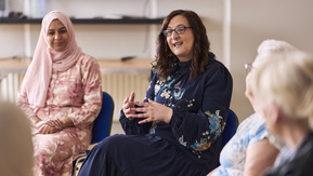 People sitting in a support group, one person speaking while others listen in a circle