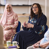 People sitting in a support group, one person speaking while others listen in a circle